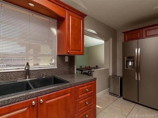 kitchen featuring sink, light tile patterned floors, decorative backsplash, and stainless steel refrigerator with ice dispenser