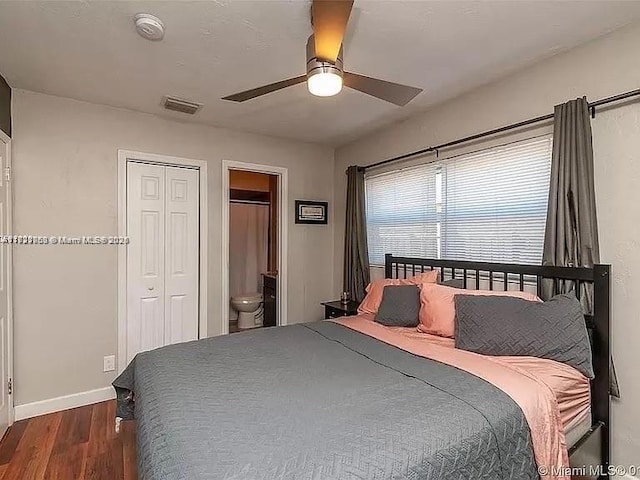 bedroom featuring connected bathroom, dark wood-type flooring, a closet, and ceiling fan