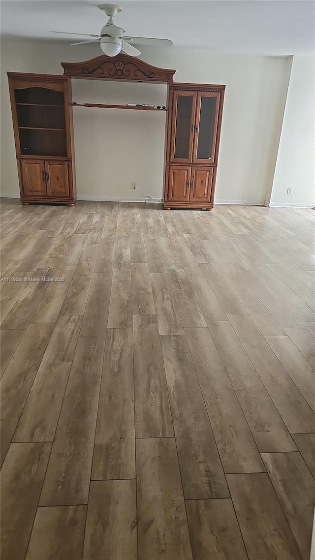 unfurnished living room featuring ceiling fan and light wood-type flooring