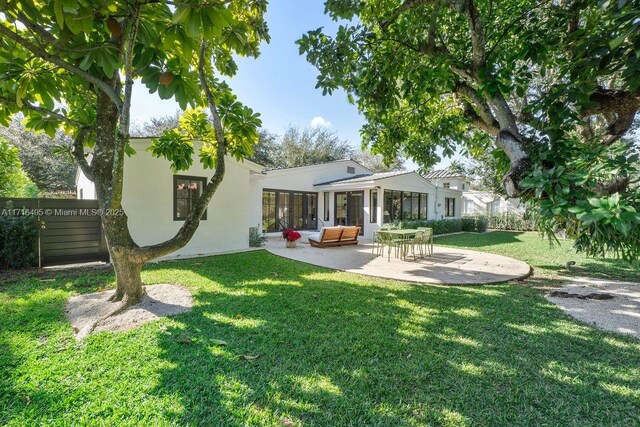 back of house with a lawn and a patio