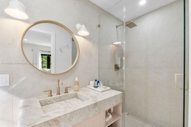 bathroom featuring vanity, a shower with door, and tile walls