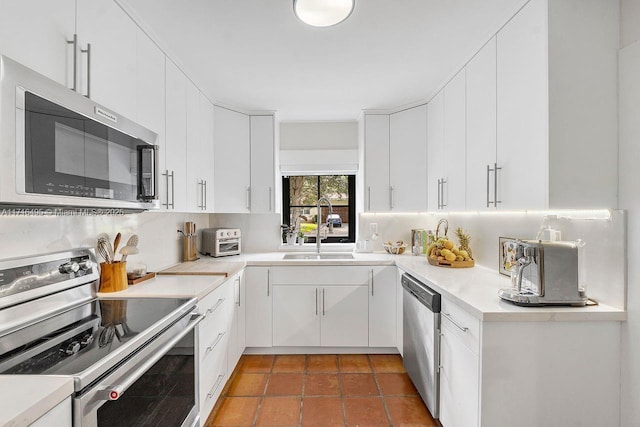 kitchen featuring tasteful backsplash, white cabinetry, appliances with stainless steel finishes, and sink