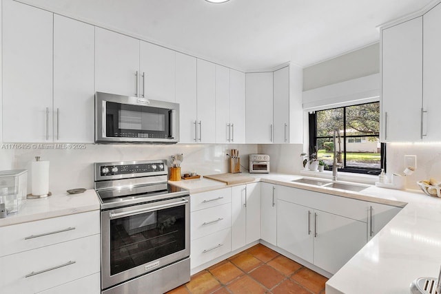 kitchen featuring white cabinetry, stainless steel appliances, sink, and backsplash