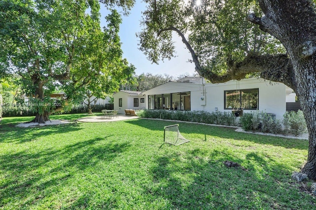 back of house with a lawn and a patio