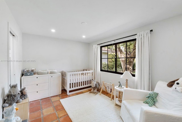 bedroom featuring light tile patterned floors and a nursery area