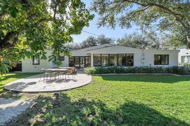 rear view of house with a patio and a lawn