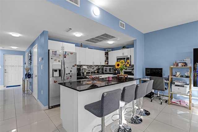 kitchen with tasteful backsplash, a breakfast bar, stainless steel appliances, white cabinetry, and light tile patterned flooring