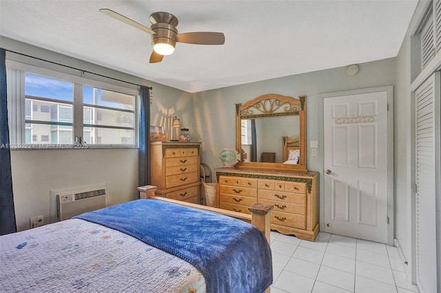 bedroom featuring ceiling fan, a closet, light tile patterned flooring, and a wall mounted air conditioner