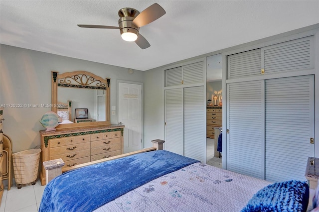 tiled bedroom with ceiling fan and a textured ceiling