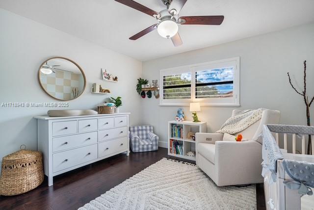 bedroom with ceiling fan, dark hardwood / wood-style floors, and a crib