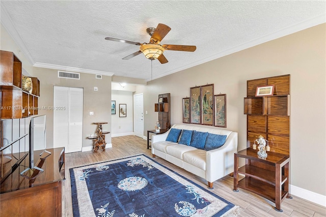 living room with ceiling fan, crown molding, light hardwood / wood-style floors, and a textured ceiling