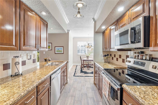 kitchen featuring backsplash, sink, appliances with stainless steel finishes, decorative light fixtures, and a chandelier