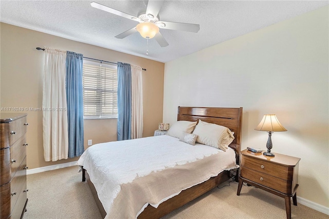 bedroom with a textured ceiling, light colored carpet, and ceiling fan