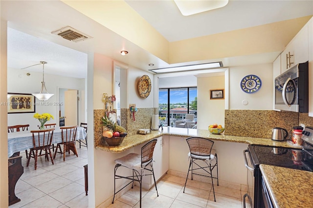 kitchen with a breakfast bar, kitchen peninsula, stainless steel appliances, and white cabinetry