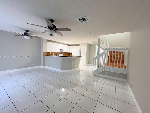 interior space with ceiling fan, light tile patterned floors, and a textured ceiling