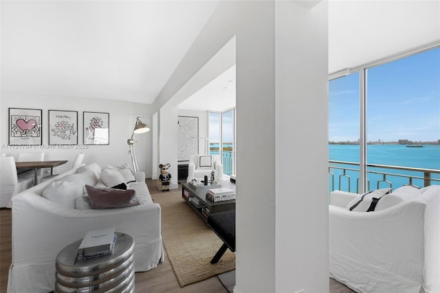 living room featuring wood-type flooring, a water view, and a wall of windows