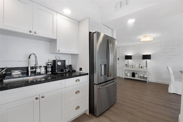 kitchen featuring dark hardwood / wood-style flooring, sink, dark stone countertops, white cabinets, and stainless steel fridge with ice dispenser