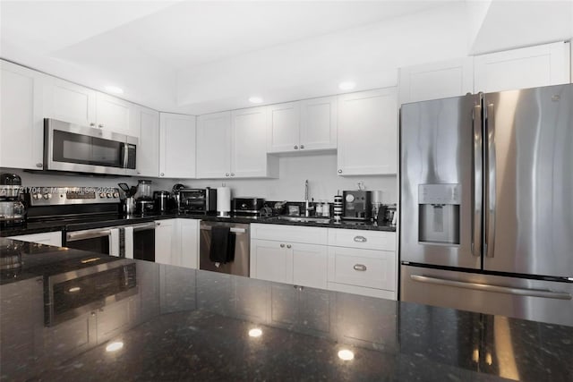 kitchen with white cabinetry, sink, dark stone counters, and appliances with stainless steel finishes