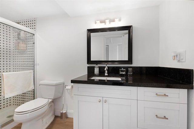 bathroom featuring hardwood / wood-style floors, vanity, toilet, and a shower with shower door