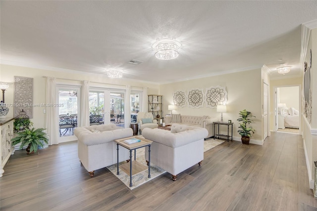 living room featuring ornamental molding, french doors, hardwood / wood-style floors, and a notable chandelier