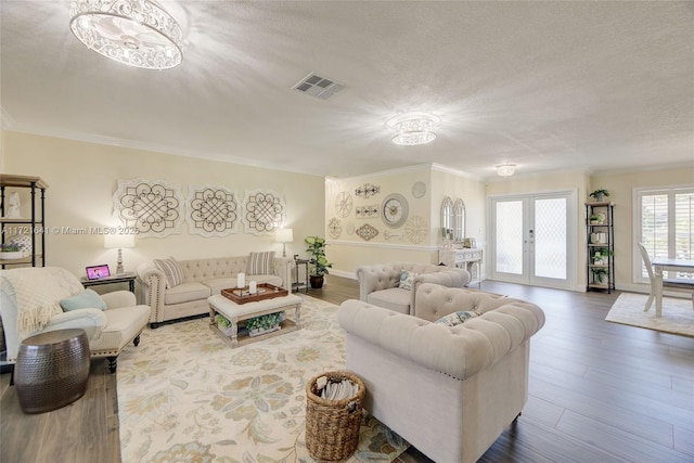 living room with a textured ceiling, french doors, crown molding, and hardwood / wood-style flooring