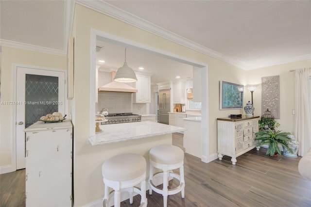 kitchen with white cabinets, custom range hood, ornamental molding, range, and hanging light fixtures