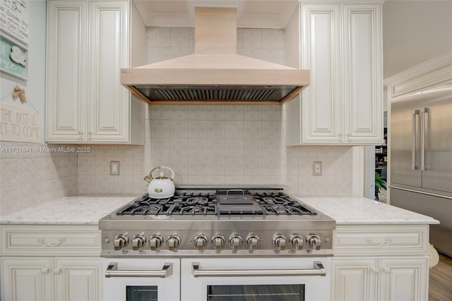 kitchen featuring white cabinets, light stone counters, decorative backsplash, premium range hood, and high quality appliances