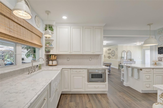 kitchen featuring hanging light fixtures, white cabinetry, hardwood / wood-style floors, and tasteful backsplash