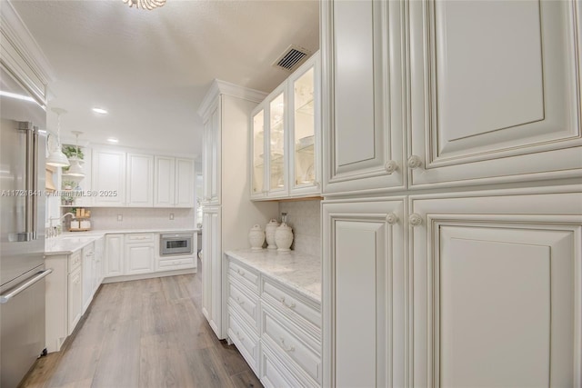 kitchen featuring light stone counters, light hardwood / wood-style flooring, decorative backsplash, and white cabinetry