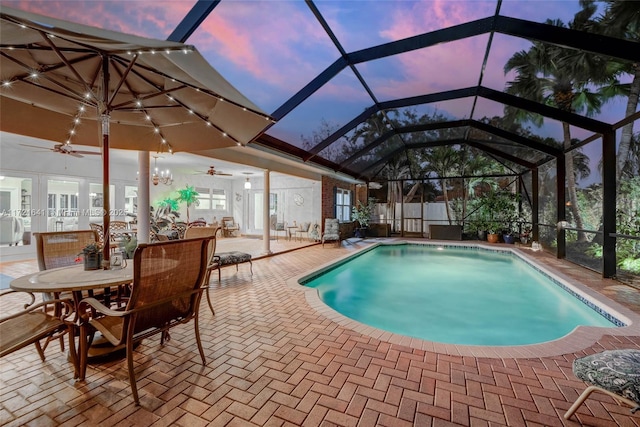 pool at dusk with glass enclosure and a patio