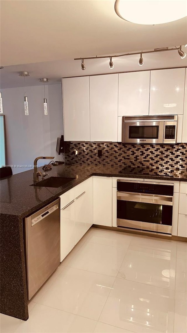 kitchen featuring white cabinets, sink, decorative backsplash, appliances with stainless steel finishes, and decorative light fixtures