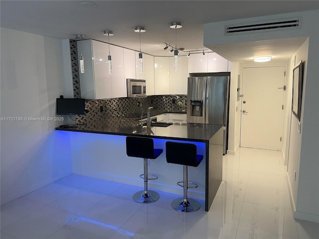 kitchen featuring white cabinets, sink, decorative backsplash, appliances with stainless steel finishes, and kitchen peninsula