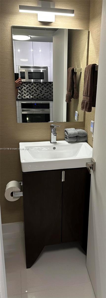 bathroom featuring backsplash, tile patterned flooring, and vanity