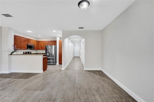 kitchen featuring light wood-type flooring, kitchen peninsula, and appliances with stainless steel finishes