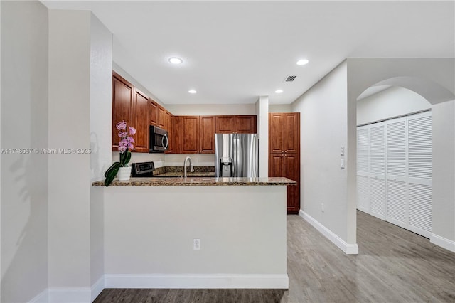 kitchen featuring light stone countertops, sink, stainless steel appliances, kitchen peninsula, and light hardwood / wood-style floors