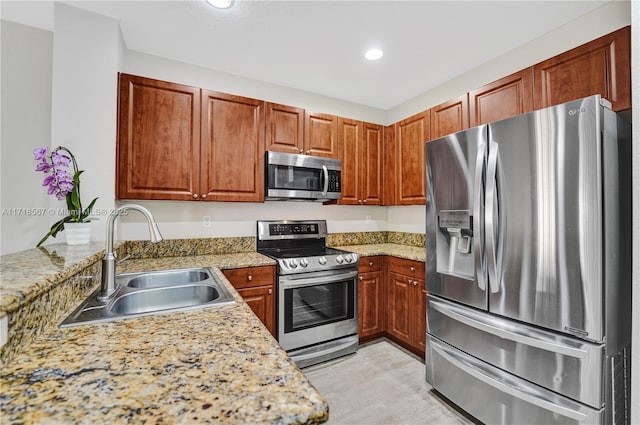 kitchen featuring kitchen peninsula, appliances with stainless steel finishes, light stone counters, and sink