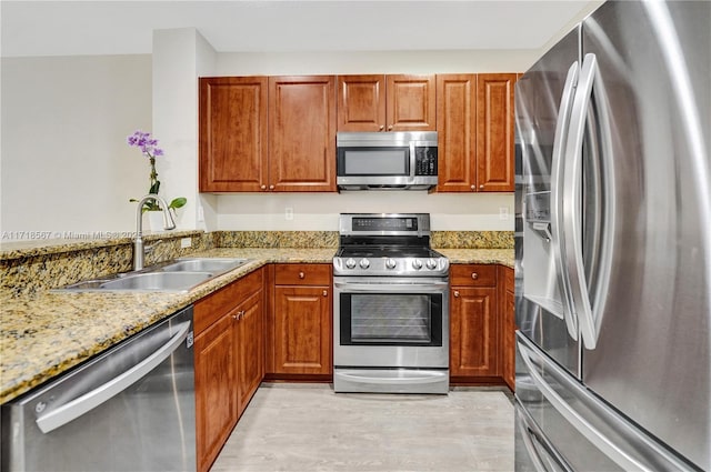 kitchen featuring light stone countertops, appliances with stainless steel finishes, light wood-type flooring, and sink