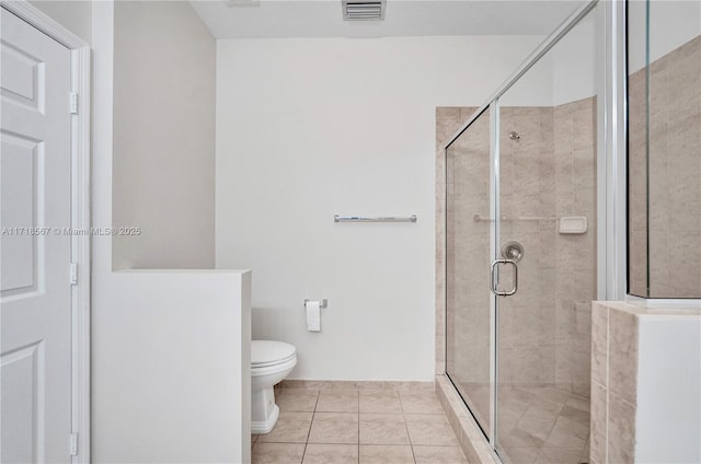 bathroom featuring tile patterned floors, toilet, and a shower with door