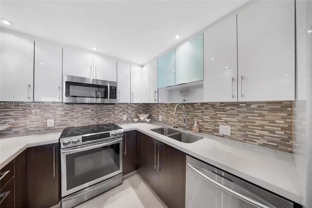 kitchen with backsplash, sink, light tile patterned floors, white cabinetry, and stainless steel appliances