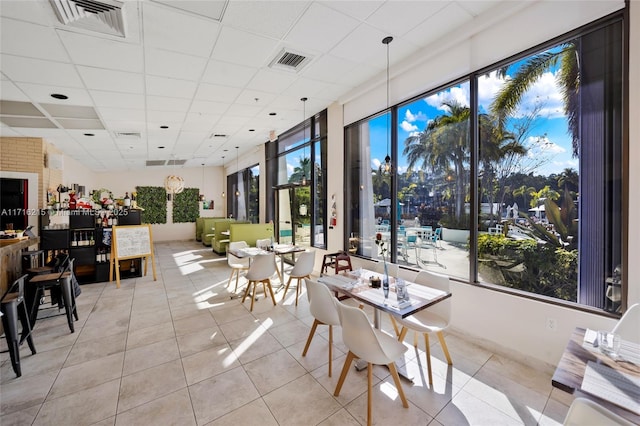 dining area with a paneled ceiling and light tile patterned flooring