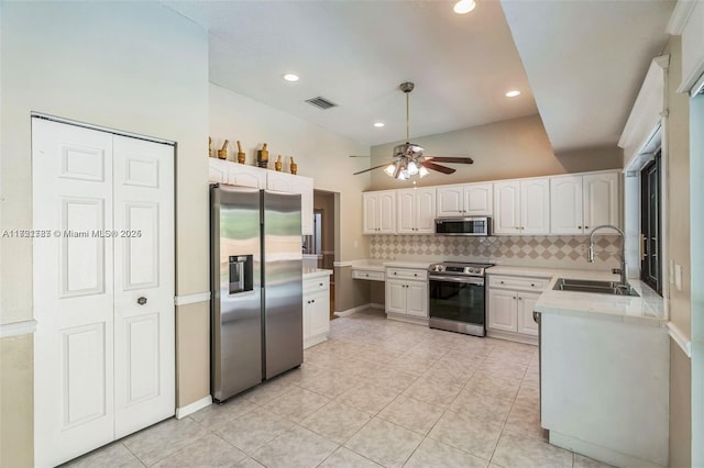 kitchen with decorative backsplash, stainless steel appliances, ceiling fan, sink, and white cabinets