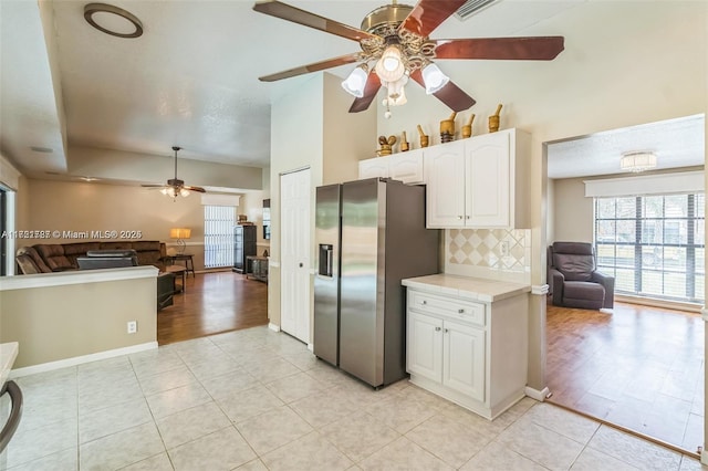 kitchen with white cabinets, stainless steel refrigerator with ice dispenser, ceiling fan, light tile patterned floors, and tasteful backsplash