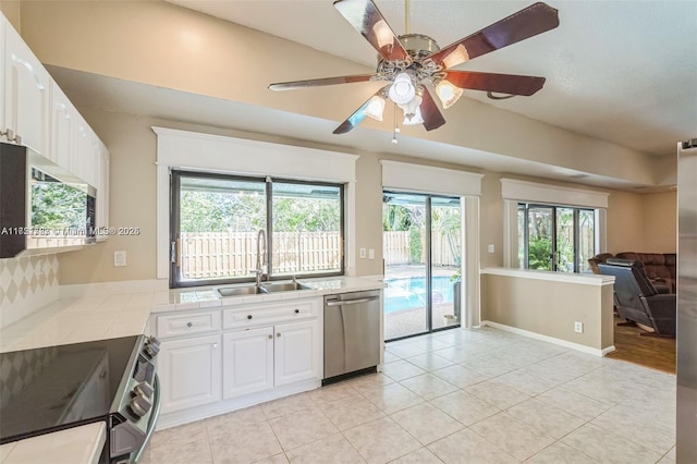 kitchen featuring appliances with stainless steel finishes, ceiling fan, sink, light tile patterned floors, and white cabinetry