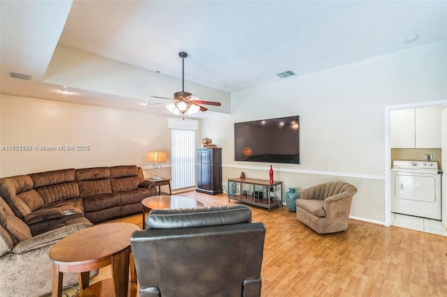 living room with washer / clothes dryer, ceiling fan, and light hardwood / wood-style flooring