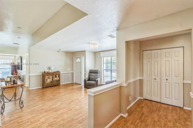 hall with light hardwood / wood-style flooring and a textured ceiling