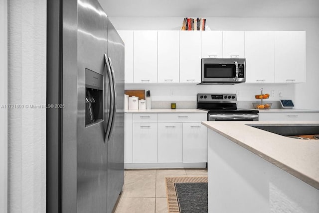 kitchen with light tile patterned flooring, white cabinetry, and appliances with stainless steel finishes