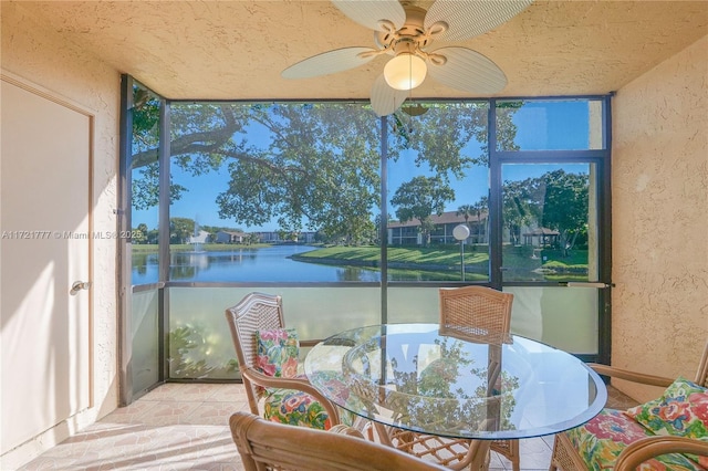 sunroom / solarium with ceiling fan and a water view