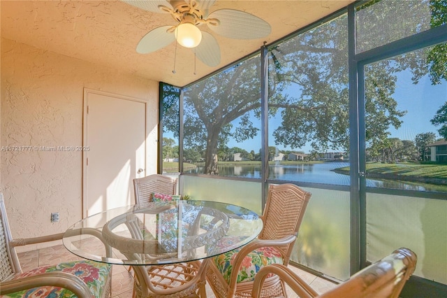 sunroom featuring ceiling fan and a water view