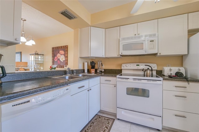 kitchen with white appliances, sink, light tile patterned floors, a chandelier, and white cabinetry