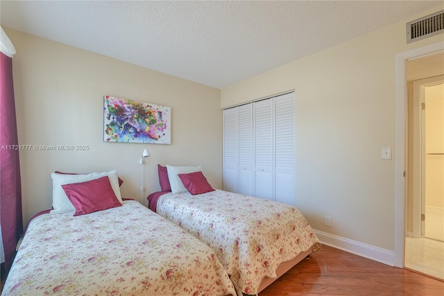 bedroom with hardwood / wood-style floors, a textured ceiling, and a closet